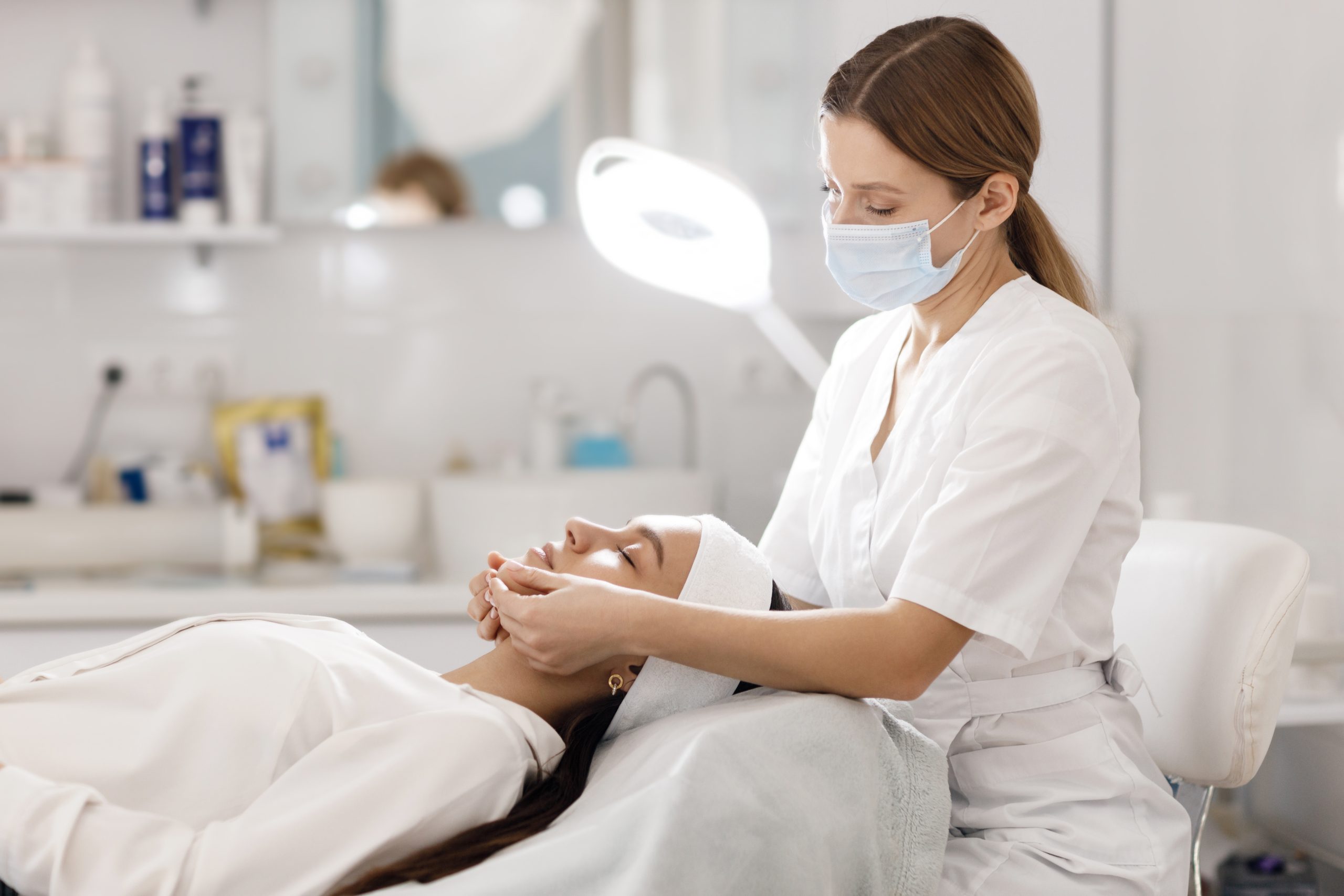 socio esthéticienne qui réalise un soin visage à l'hôpital sur une patiente